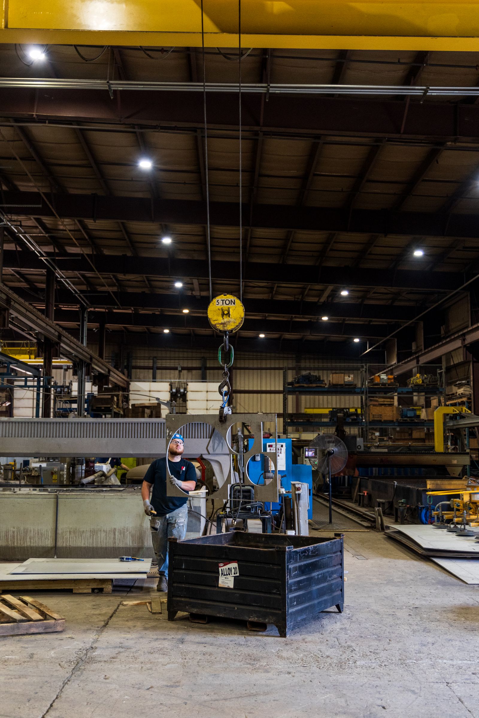 factory worker operating lifting equipment in a large industrial workshop