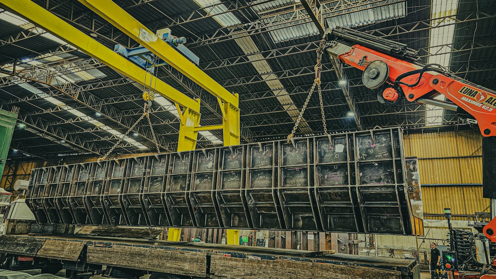 industrial overhead crane lifting a heavy metal structure inside a warehouse