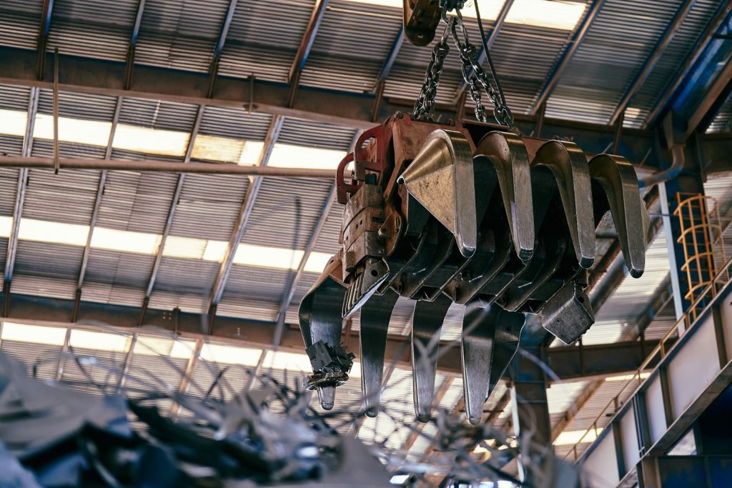 industrial crane handling scrap metal inside a warehouse