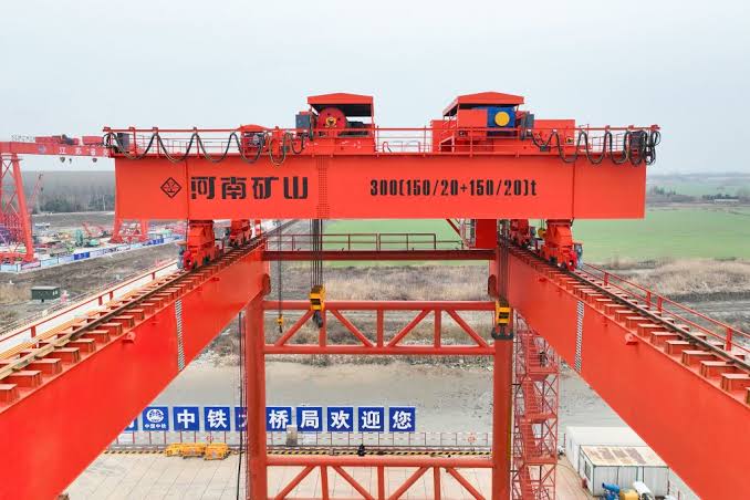 Overhead crane lifting a long workpiece